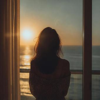 夕陽を見つめる女性の後ろ姿 夕陽を見つめる女性の後ろ姿の写真