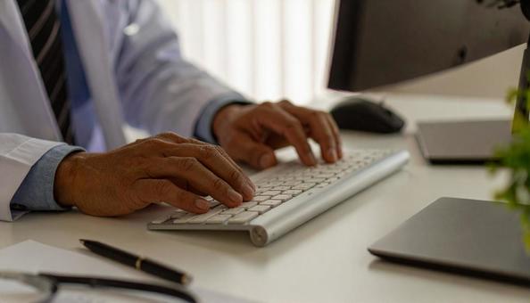 病院で電子カルテに入力する男性の手もと 病院で電子カルテに入力する男性の手もとの写真