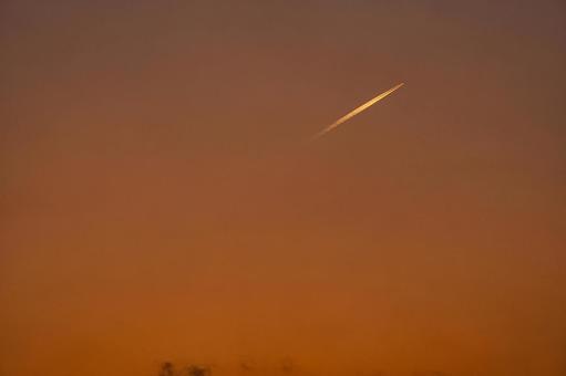 夕焼けに染まる空を飛んでいく飛行機雲 夕焼け,夕暮れ,夕方の写真素材