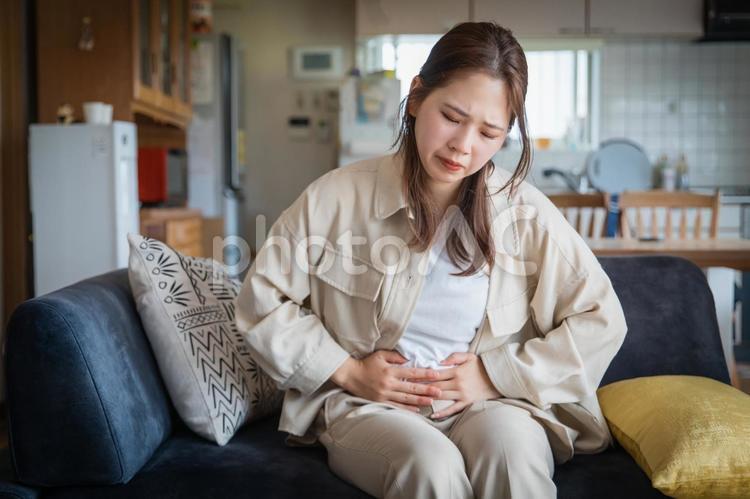 自宅でお腹を痛めて苦しそうな女性 腹痛,生理痛,女性の写真素材
