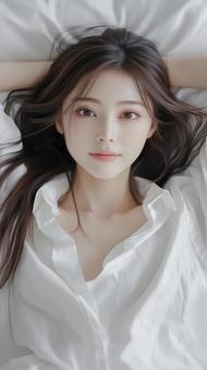 ベッドに仰向けに寝る笑顔が可愛い女性の写真