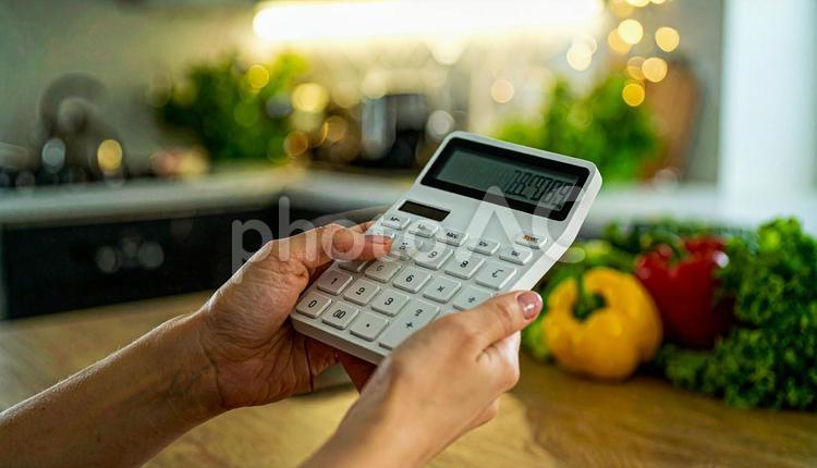 光熱費イメージ　台所で電卓を手に取る手 電卓,食費,光熱費の写真素材