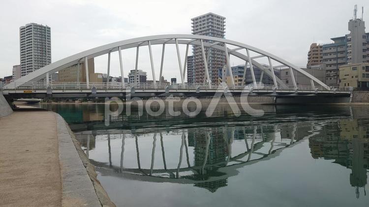 水面に反射するアーチ状の橋とビル群 橋,川,建築の写真素材