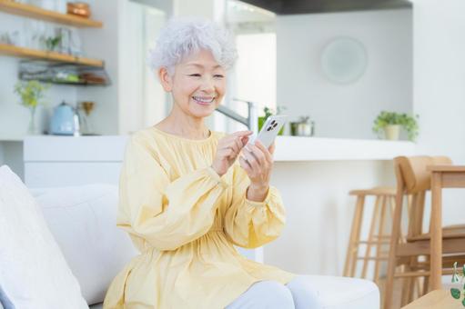 リビングでスマホを見るシニアの女性 リビングでスマホを見るシニアの女性 シニア,女性,老後の写真素材