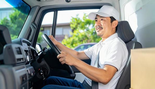 トラックを運転する男性ドライバーの横顔 トラックを運転する男性ドライバーの横顔の写真