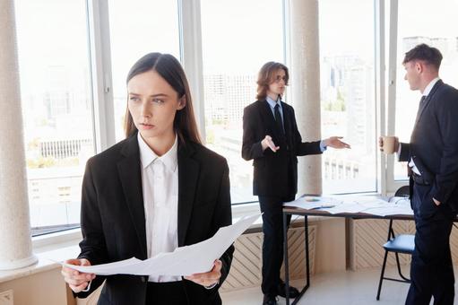 書類を持ち立つ女性と立ち話をする男性たち 男女,女性,資料の写真素材