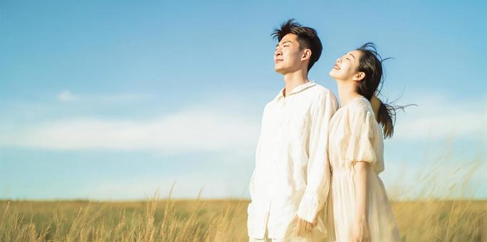 青空の下、草原に佇む二人 青空の下、草原に佇む二人の写真