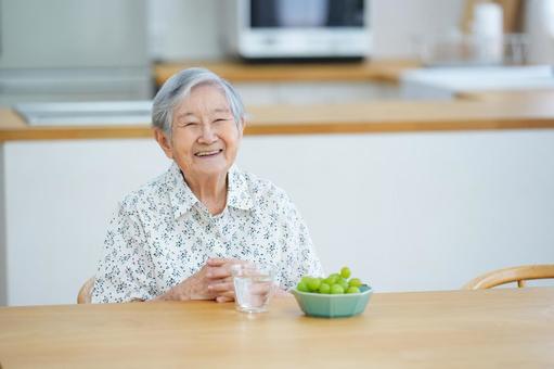 椅子に座り笑うおばあちゃん 女性,シャインマスカット,ぶどうの写真素材