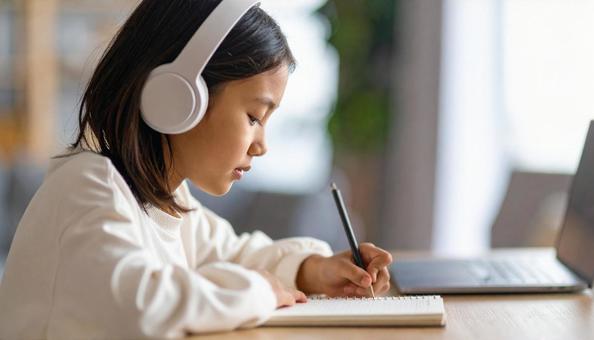 お気に入りの音楽を聴きながら勉強する女性 お気に入りの音楽を聴きながら勉強する女性の写真