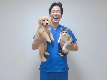 子犬と猫を両腕に抱えて笑顔を見せる獣医師 男性,ペット,獣医師の写真素材