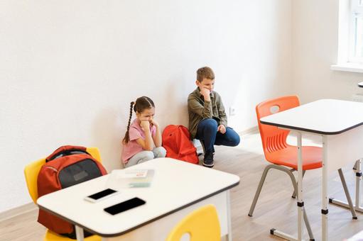 教室でしゃがんで考える生徒たち 男の子,女の子,子どもの写真素材