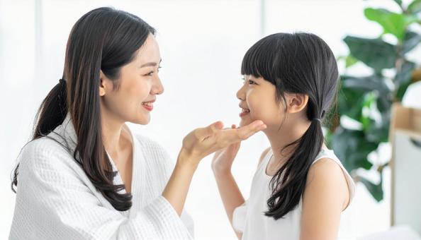 娘の頬を触る母娘のビューティーイメージの写真