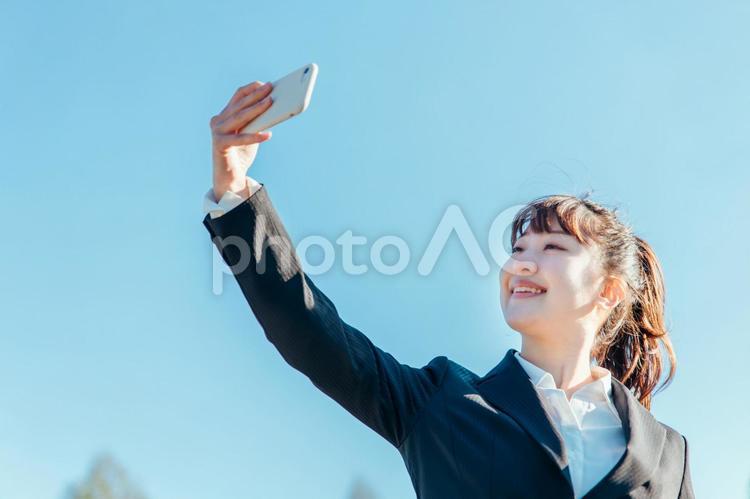 スマホをかざすビジネスウーマン（逆光） スマホ,自撮り,セルフィーの写真素材