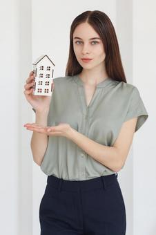 家の模型を紹介する女性スタッフ 保険業,事務職,接客業の写真素材