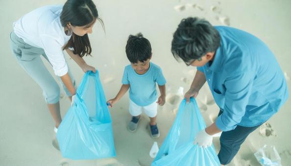 ボランティアで海辺のごみ拾いをする親子 ボランティアで海辺のごみ拾いをする親子の写真
