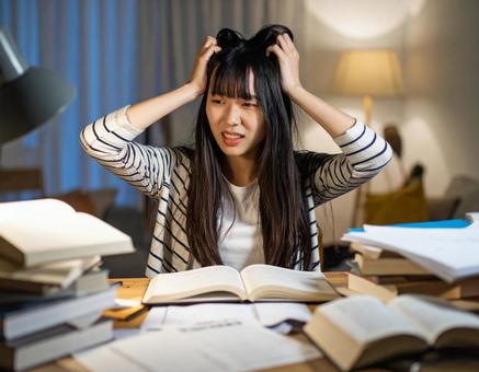 試験勉強中に頭を抱える女子学生の写真