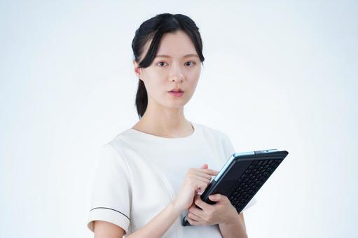 女性がタブレットを持って立つ 女性,タブレット,持つの写真素材