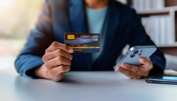 手にスマホとクレジットカードを持つ女性の写真