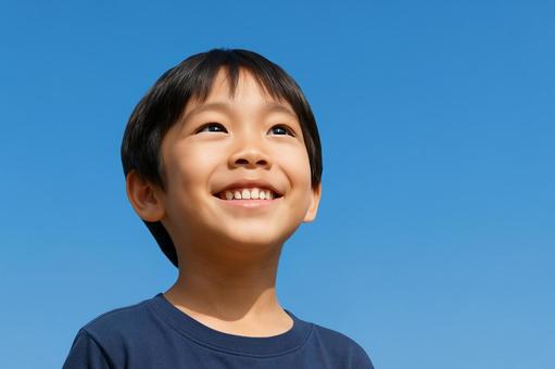 青空と笑顔の楽しそうな小学生の子ども 青空と笑顔の楽しそうな小学生の子どもの写真