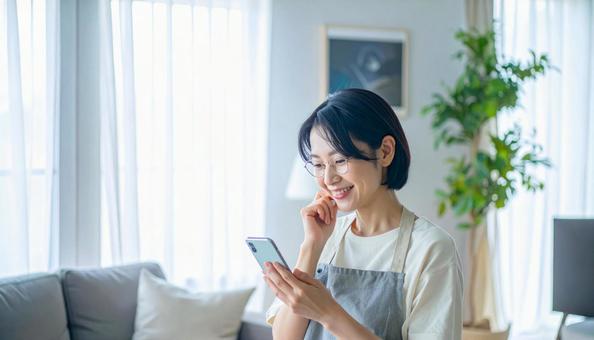 スマホでポイ活する笑顔の女性 スマホでポイ活する笑顔の女性の写真