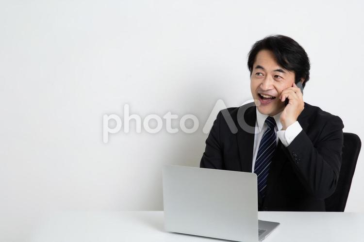 電話をしながら仕事をしている中年のサラリーマン男性（コピースペース） 中年,上司,会社員の写真素材