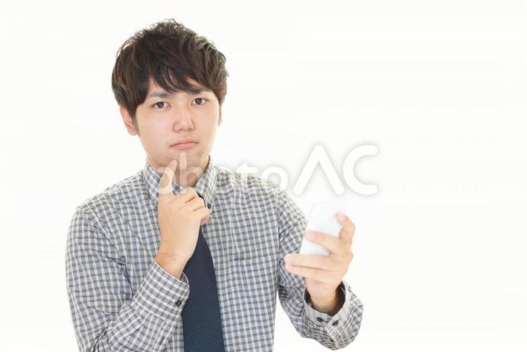 スマートフォンを持つ不安そうな表情の男性 男性,ビジネスマン,男の写真素材