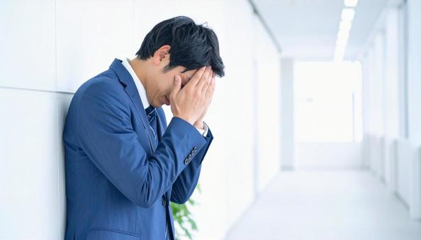 オフィスビルの廊下で苦悩するビジネスマンの写真