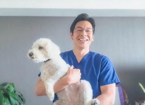 犬を抱っこする動物ケアスタッフの男性 男性,笑顔,犬の写真素材