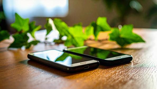 連絡交換のイメージ 机の上の携帯電話二台 連絡交換のイメージ 机の上の携帯電話二台の写真