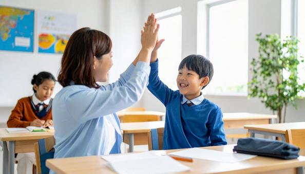 ハイタッチする塾講師と小学生の男の子 ハイタッチする塾講師と小学生の男の子の写真