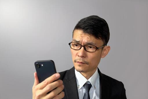 スマホを真剣にチェックするビジネスマン 男性,日本人,人物の写真素材