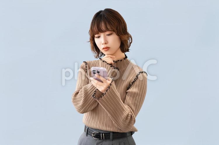 スマホを見て考える女性・ビジネスウーマン 女性,困る,考えるの写真素材