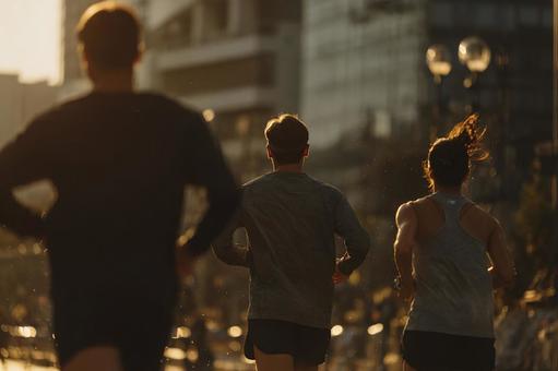 夕日に向かって走る3人のランナーの写真
