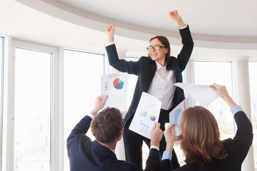 中央で喜ぶ女性と書類を持つ2人 女性,男女,外国人の写真素材