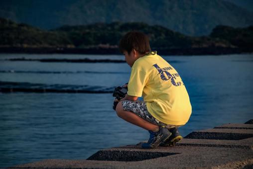<Material> A boy taking a photo of the sea at dusk from the embankment, JPG