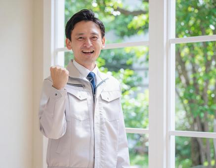 作業服を着てガッツポーズする男性 作業服を着てガッツポーズする男性の写真
