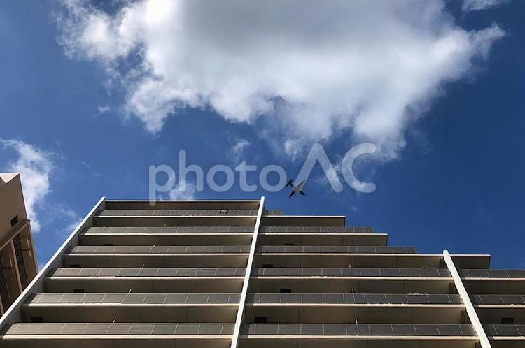 マンションの上を飛ぶ飛行機 飛行機,空,青空の写真素材