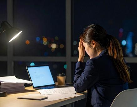 残業が終わらず頭を抱える女性 残業が終わらず頭を抱える女性の写真