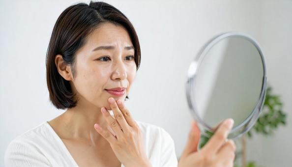 ビューティーイメージ　鏡を見て悩む女性の写真
