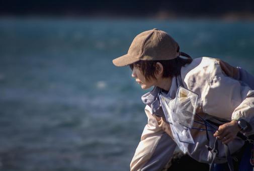 ＜素材＞磯でガサガサ（小魚捕獲）する女性 女性,磯遊び,海の写真素材