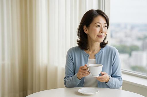 ホテルで外を眺めながらお茶を飲む中年女性 ホテルで外を眺めながらお茶を飲む中年女性の写真