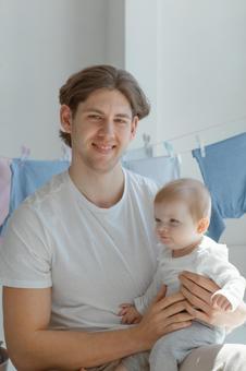 カメラ目線で赤ちゃんを抱っこする男性 カメラ目線で赤ちゃんを抱っこする男性 親子,男性,抱っこの写真素材