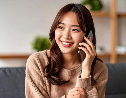 自宅のリビングで通話をする女性 自宅のリビングで通話をする女性の写真