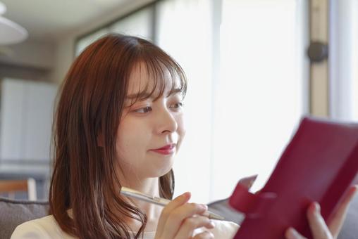 リビングで手帳の予定を確認する女性 リビングで手帳の予定を確認する女性 ノート,手帳,スケジュール帳の写真素材