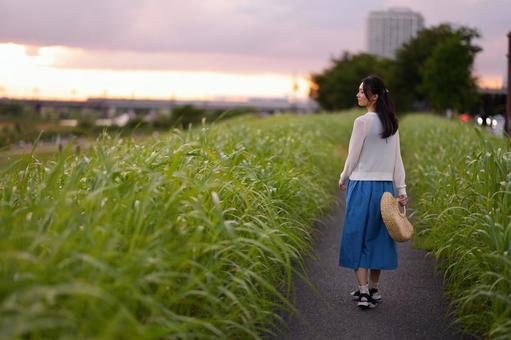 夕暮れを歩く青いスカートの女性 女性,振り向く,横顔の写真素材