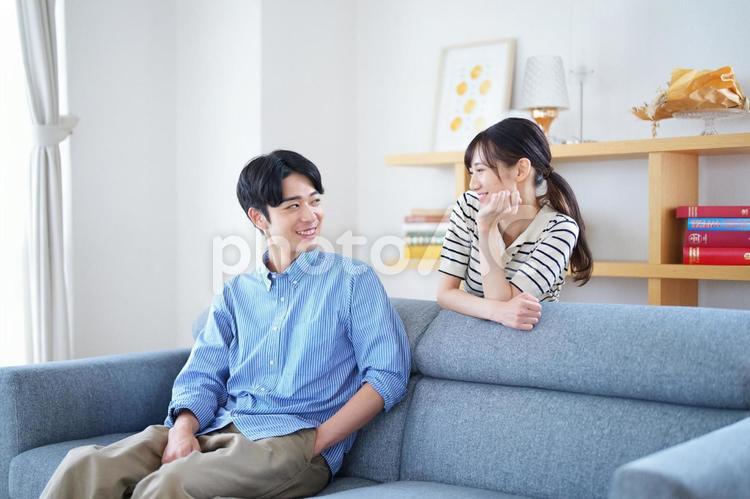 ソファに座る男性と話す女性 男女,ソファ,座るの写真素材