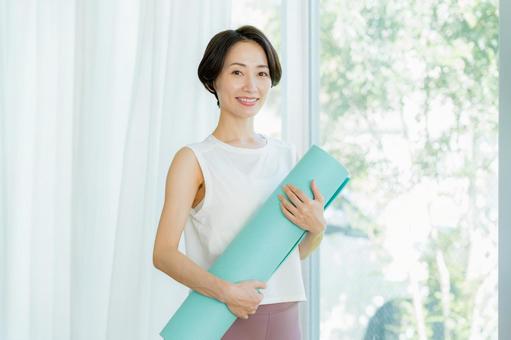 リビングでヨガをする女性 リビングでヨガをする女性 ミドル,持つ,ヨガマットの写真素材