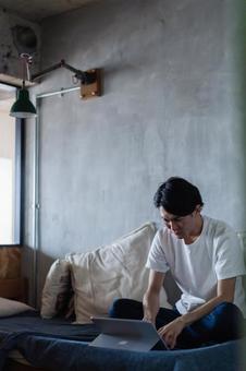 ベッドで在宅勤務をする若い男性 フリーランス,テレワーク,家の写真素材