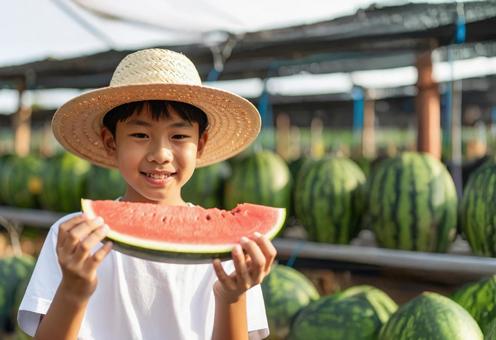農家でスイカをもらって食べる男の子の写真