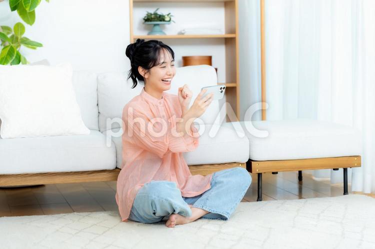 部屋でスマホを操作する若い女性 部屋でスマホを操作する若い女性 スマホ,若い女性,笑顔の写真素材